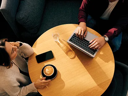 two people sitting down coffee table with mobile and laptop